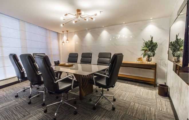 Sala de reunião do escritório, com mesa de vidro e poltronas em couro